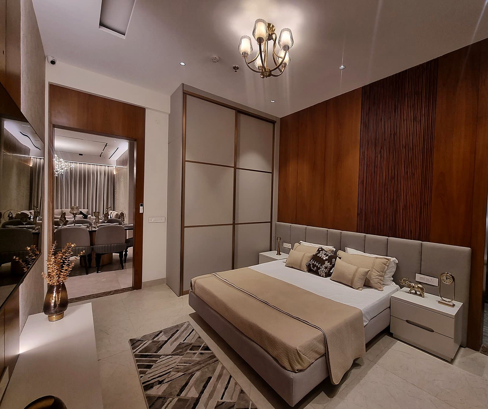 Bedroom with walnut wood accent wall, sliding wardrobe and brass chandelier in premium Mohali flat