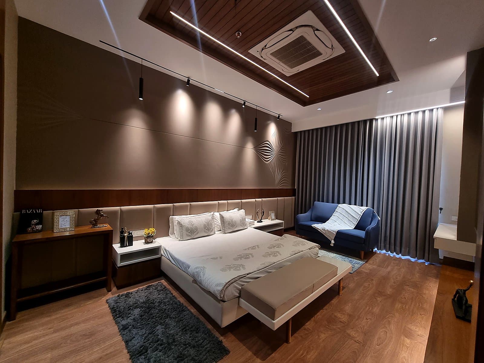 Bedroom with track lighting, wooden ceiling panel and blue armchair in 4+1 BHK Mohali flat