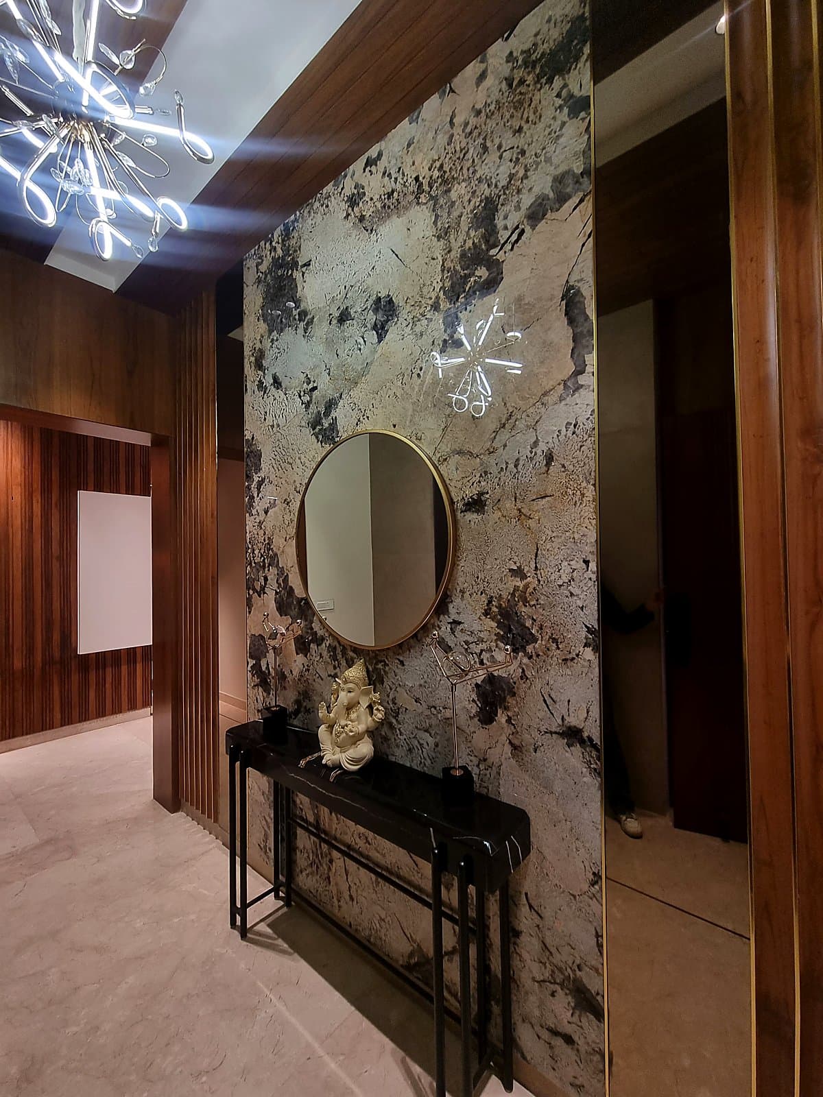 Grand entrance foyer with marble accent wall, round mirror and Sputnik chandelier in Mohali property