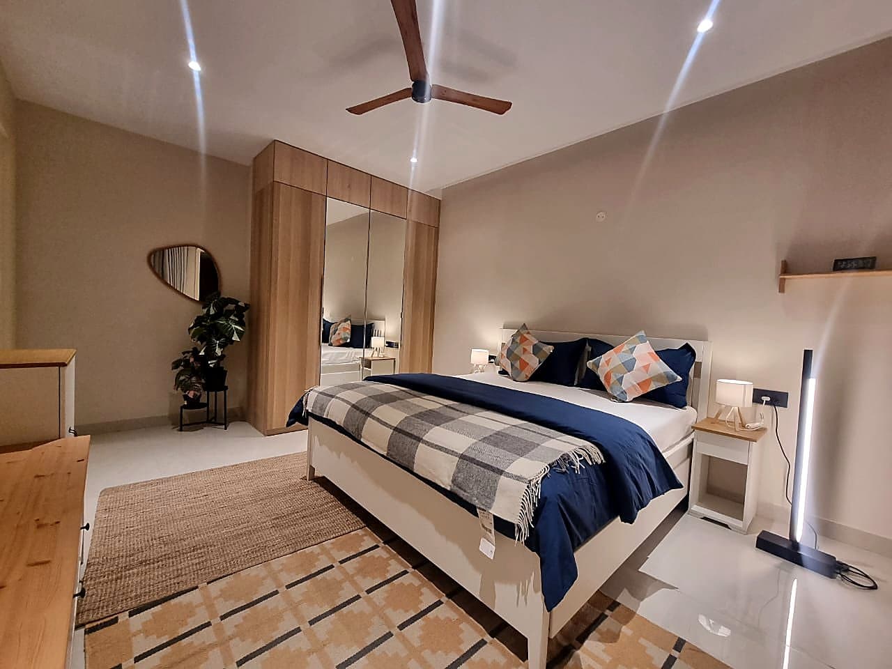Guest bedroom with navy blue bedding and mirrored wardrobe in Zirakpur smart home apartment