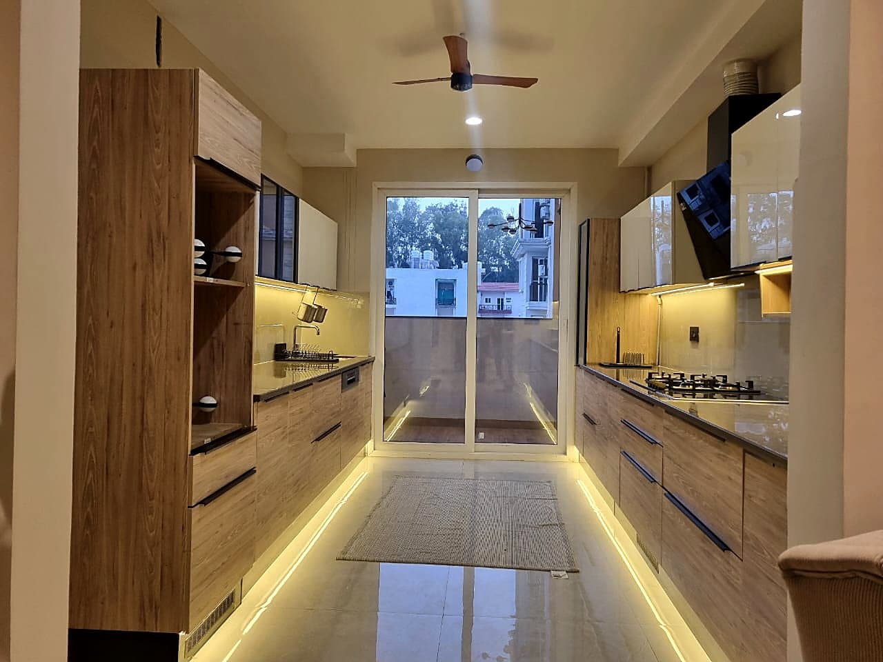 Modular kitchen with wood finish cabinets and LED under-cabinet lighting in smart home Zirakpur flat