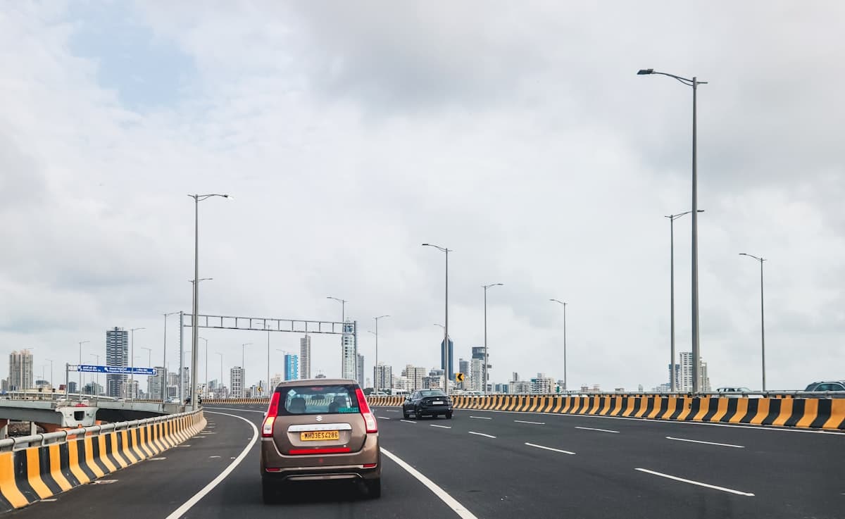 Indian highway connecting to city with Maruti Suzuki car and skyline
